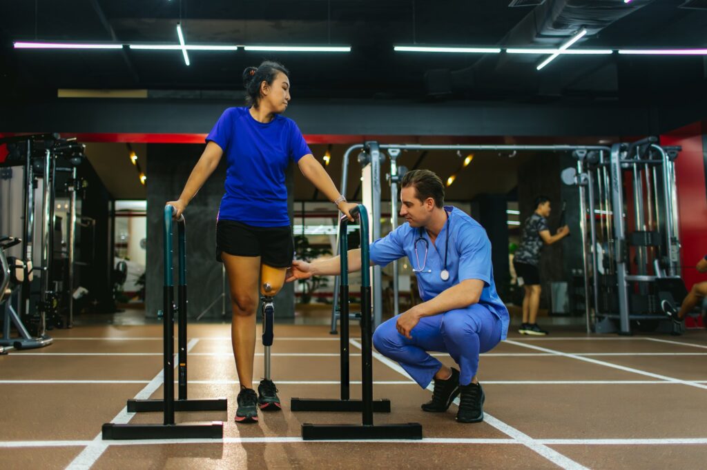 Physiotherapist take care patient and prosthetic leg during physical therapy after amputation recovery