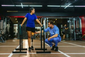 Physiotherapist take care patient and prosthetic leg during physical therapy after amputation recovery