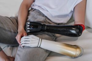 Man sitting down wearing custom prosthetics hand and also holding another custom prosthetic hand