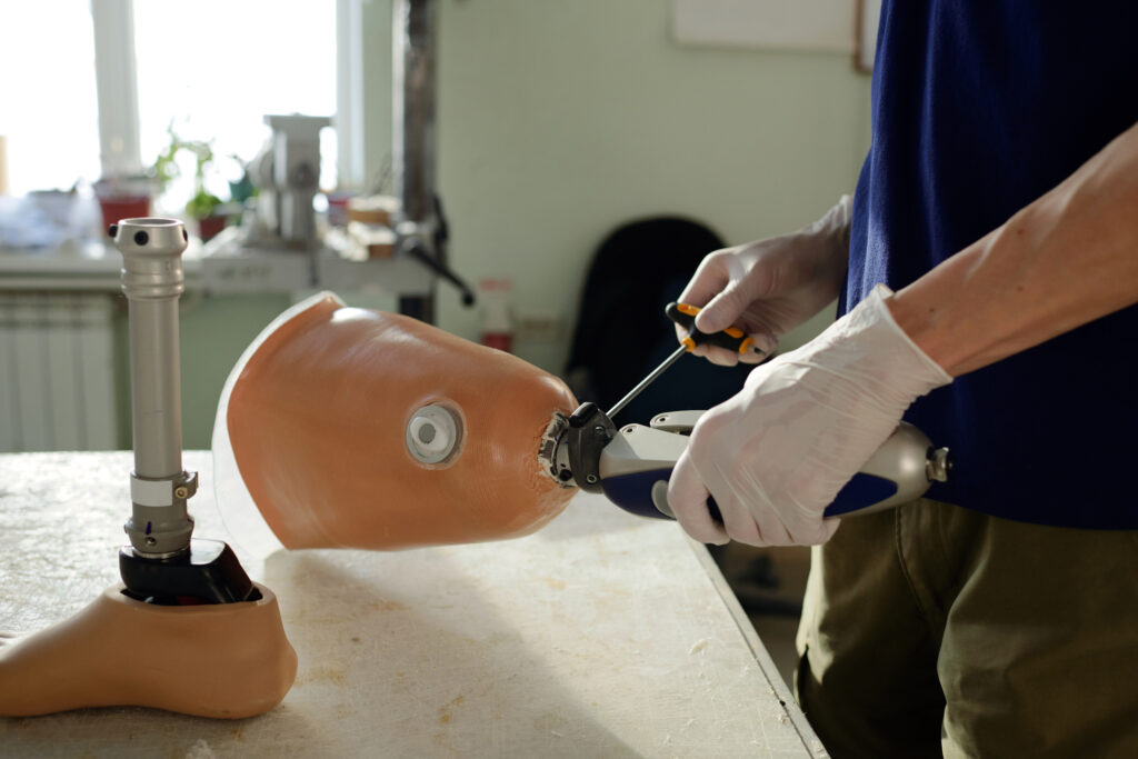 Technician adjusting a prosthetic leg using tools in a clinical setting