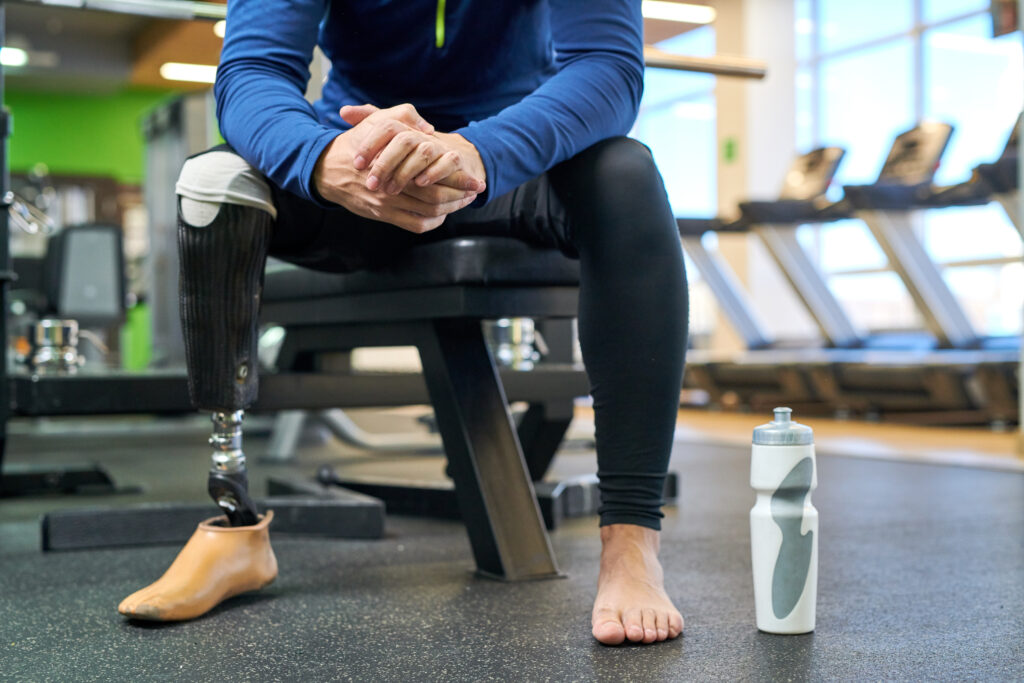 Athlete with prosthetics resting on a bench after a workout in a fitness center