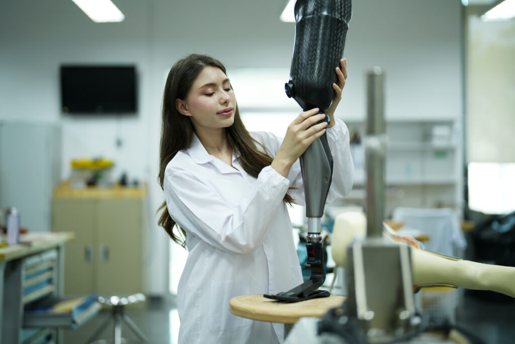 Prosthetics technician adjusting a custom prosthetic leg during fabrication in a clinical lab