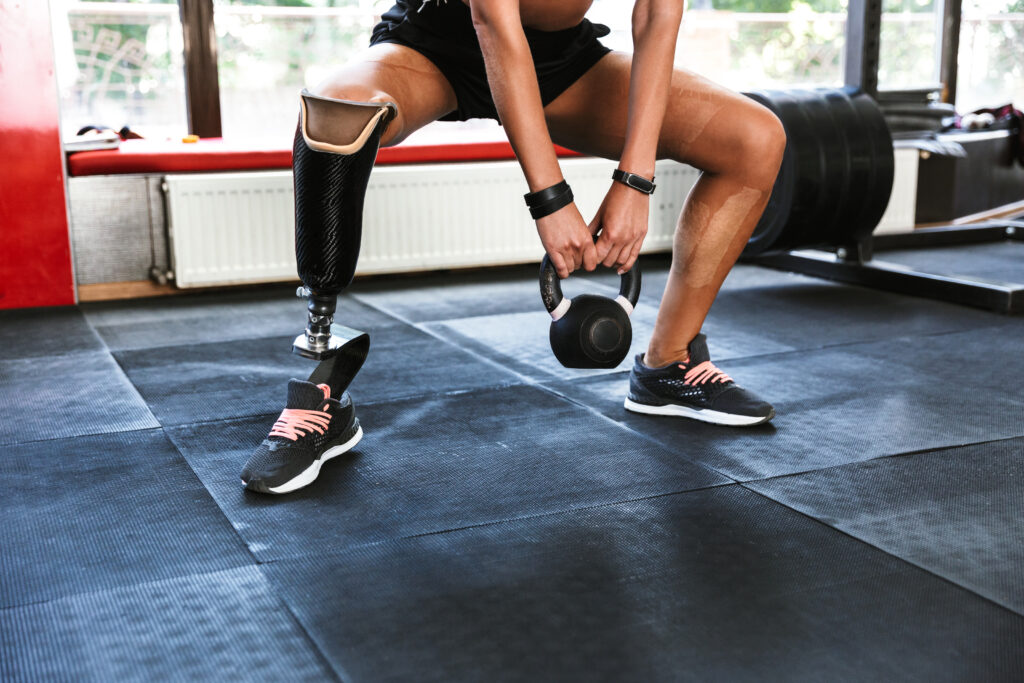 Athletic woman using prosthetics performing strength training with a kettlebell